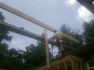 Carpenter setting a ridge beam over a new addition frame — Ice Dam Removal by Roofing Brothers in Clarissa
