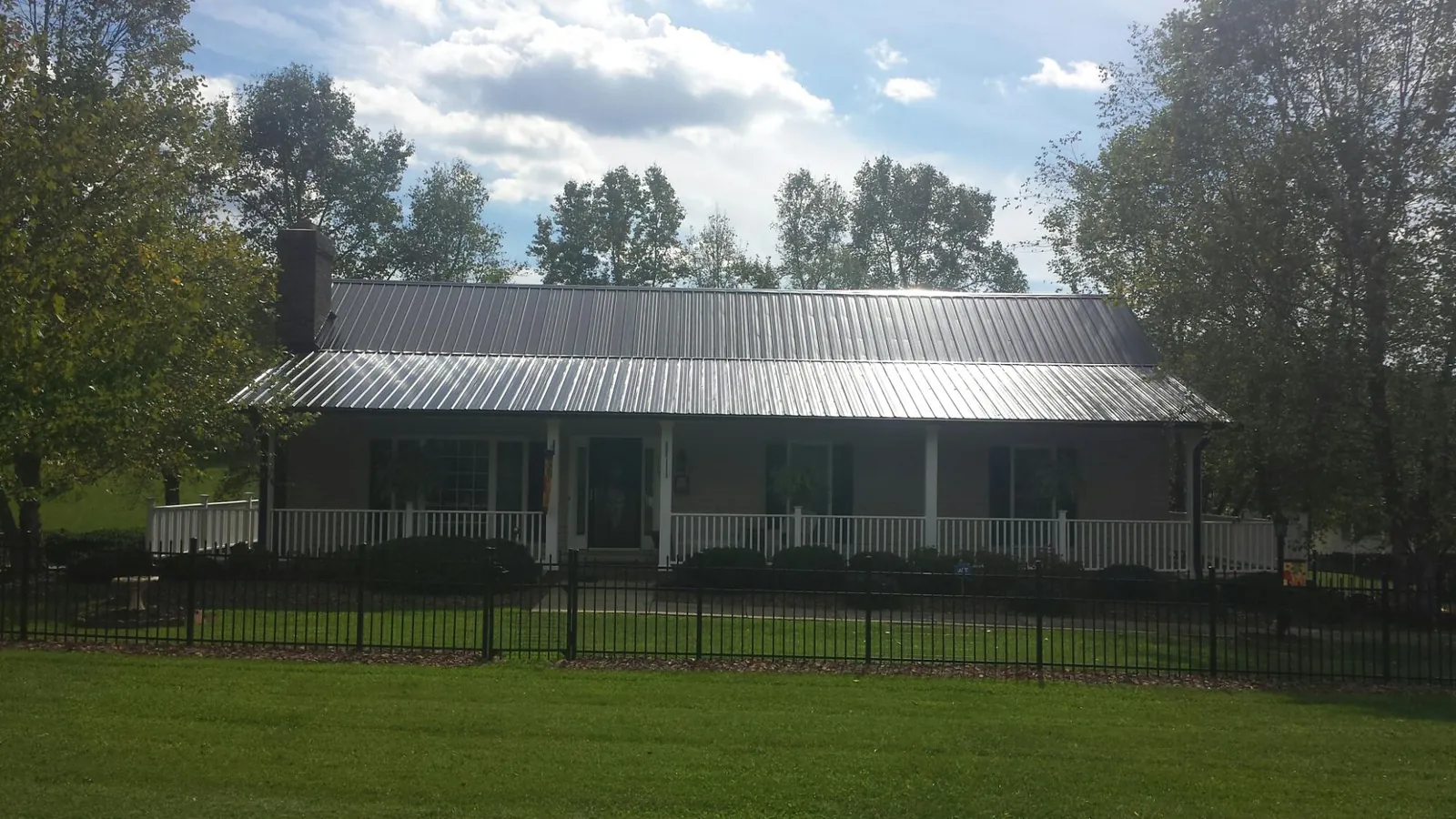Gray metal roof on a brick ranch with a full width front porch — Gutter Guard Installation work by our crew in Clarissa