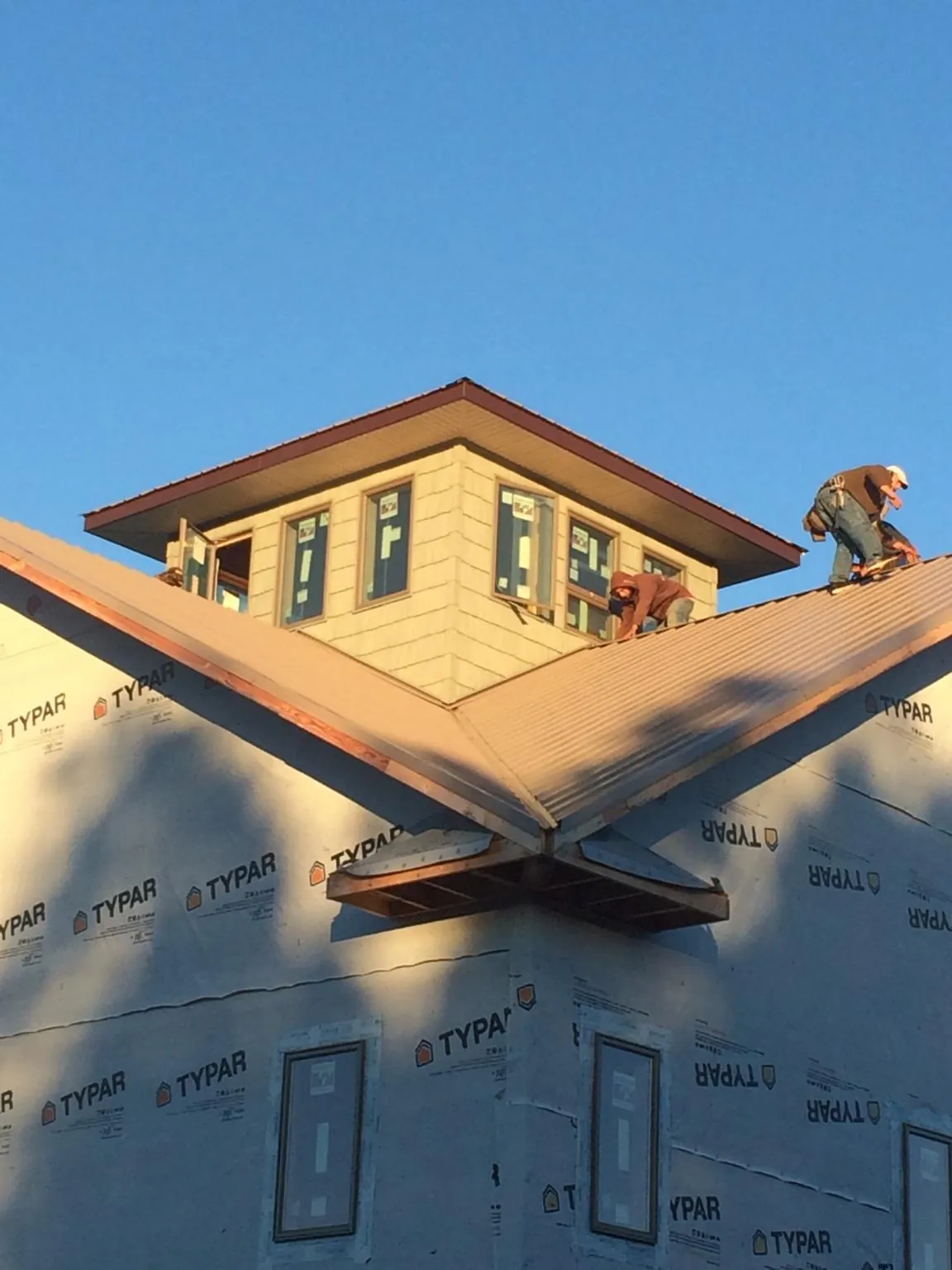 Roofers working around a rooftop cupola on a new metal roof at sunset — Roof Waterproofing in Clarissa by Roofing Brothers